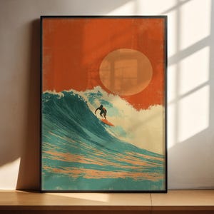 May include: Framed art print depicting a surfer on a wave. The artwork has a vintage style, with an orange sky and a large sun. The wave is teal and white, and the surfer is a black silhouette. The print is in a black frame, suitable for any room.