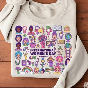 Puede incluir: Una taza de cerámica blanca con un asa negra y el texto "But First, Coffee" en negrita negra. La taza se encuentra sobre un fondo borroso, sugiriendo un ambiente acogedor.