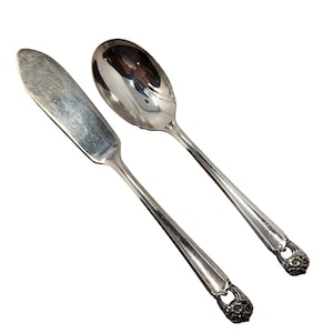 Può includere: Una tazza di ceramica bianca con un manico nero e la scritta "But First, Coffee" in nero, con un carattere a mano. La tazza è su una superficie bianca.