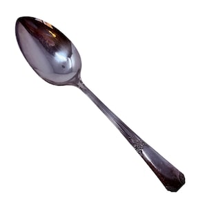 May include: A silver spoon with a reflective, oval bowl and a long, slender handle. The handle features a decorative floral pattern near the base and a rectangular end. The spoon is designed for serving or eating.