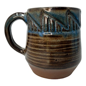 May include: A set of three ceramic mugs with a speckled, matte finish. The mugs are in shades of cream, light gray, and dark gray. Each mug has a simple, minimalist design, perfect for coffee or tea.