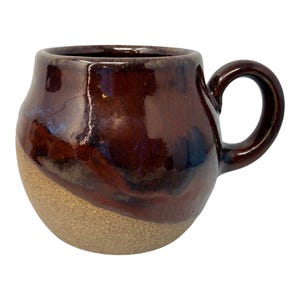 Taza grande de cerámica artesanal de estudio con esmalte marrón por goteo y diseño de símbolo de la paz.