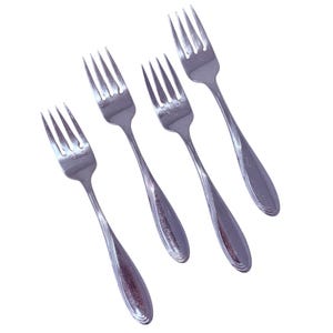 May include: Four stainless steel forks with a polished finish. Each fork has four tines and a teardrop-shaped handle with a subtle, ridged design. The forks are arranged diagonally against a white background, suggesting a dining or kitchen theme.