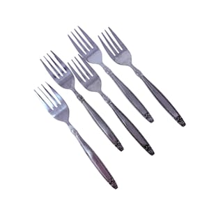 Peut inclure: Cinq fourchettes argentées avec un motif floral décoratif sur les manches. Les fourchettes sont disposées en diagonale sur un fond blanc, mettant en valeur leurs dents et leur design détaillé. Ces fourchettes sont adaptées aux repas formels.