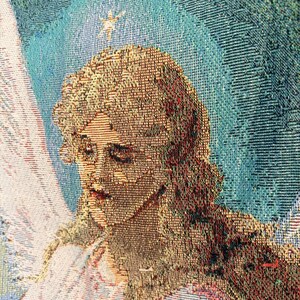Pu&ograve; includere: Primo piano di un arazzo tessuto raffigurante un angelo. L'angelo ha lunghi capelli biondi fluenti, un'espressione serena e un'aureola. Lo sfondo &egrave; una miscela di tonalit&agrave; blu e bianche.