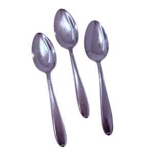 May include: Three stainless steel spoons with oval bowls and long, slender handles. The spoons are arranged diagonally against a white background, showcasing their polished, reflective surfaces. The handles have a subtle decorative pattern near the bowl.