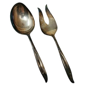 May include: A set of two silver serving utensils, a spoon and a fork, with ornate handles.