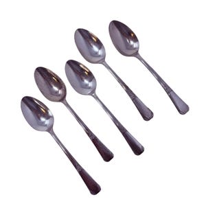 Può includere: Cinque cucchiai d'argento disposti in diagonale su sfondo bianco. I cucchiai hanno coppette ovali e manici lunghi e sottili con un motivo decorativo vicino alla base. I cucchiai sono in metallo lucido e riflettente.
