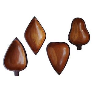 May include: Set of four wooden bowls shaped like leaves. The bowls are a dark brown colour and have a smooth, polished finish.