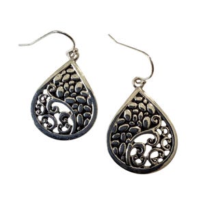 May include: A pair of silver-toned teardrop earrings. Each earring features an openwork design with a pattern of small, oval shapes and swirling filigree. The earrings have a hook closure.