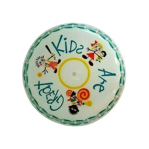 May include: A round, white button with a teal border and the words "Kids Are Great" in teal. The button features cartoon illustrations of children and a yellow circle in the center.
