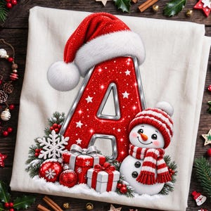 Könnte beinhalten: Ein cremefarbener Stoff mit einem großen, glitzernden roten Buchstaben A, der eine Weihnachtsmannmütze trägt. Ein lächelnder Schneemann mit rot-weiß gestreifter Mütze und Schal steht daneben, umgeben von roten Weihnachtskugeln und Geschenken.