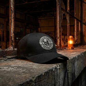 May include: Black baseball cap with a circular patch featuring a skull and the text "LUCK IS FOR HERETICS PROVERBS 16:33". The cap is set against a dark, industrial backdrop with a weathered concrete surface.