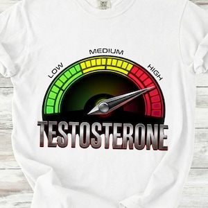 May include: White t-shirt featuring a gauge design with the word "TESTOSTERONE" in a 3D metallic font. The gauge shows "LOW" in green, "MEDIUM" in yellow, and "HIGH" in red, with a needle pointing towards the high end.