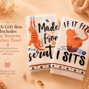 K&ouml;nnte beinhalten: Zwei wei&szlig;e K&uuml;chent&uuml;cher mit Illustrationen von orangefarbenen getigerten Katzen. Ein Tuch zeigt eine Katze mit dem Text Made from scratch, das andere eine Katze in einer Kiste mit dem Text IF IT FITS I SITS. Beide haben eine Pfotenbord&uuml;re.