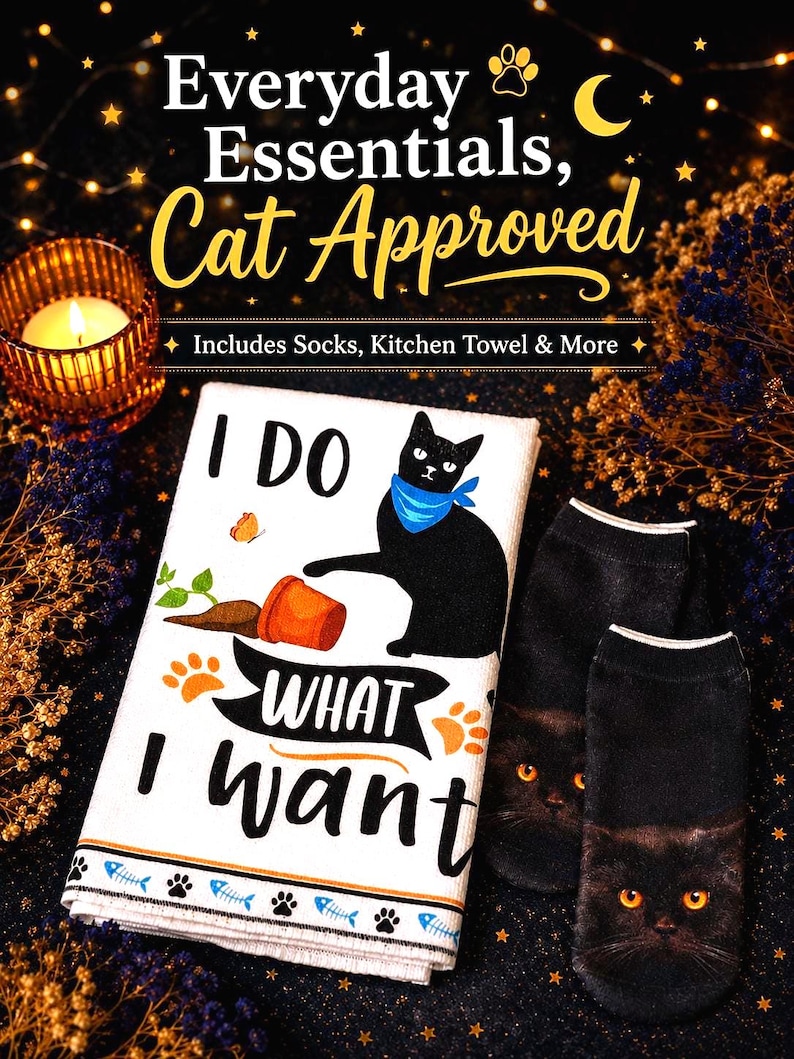K&ouml;nnte beinhalten: Ein wei&szlig;es K&uuml;chentuch mit einem schwarzen Katzenmotiv, blauem Halstuch, einem umgekippten orangefarbenen Topf und dem Text I DO WHAT I WANT, dazu ein Paar schwarze Socken mit einem realistischen Katzenkopf-Druck und leuchtend orangen Augen.