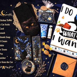 K&ouml;nnte beinhalten: Ein Geschenkset mit einem K&uuml;chentuch mit schwarzer Katze und dem Text I DO WHAT I WANT, schwarzen Katzensocken, handgemachter Seife, Handcreme, Lippenbalsam, zwei verpackten S&uuml;&szlig;igkeiten, einem Katzenstift, Lesezeichen, Kunstkarte und einem Briefumschlag.