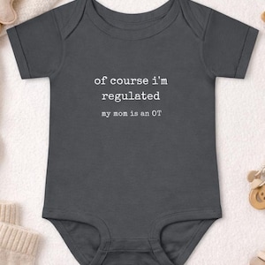May include: A dark gray baby onesie with the text "of course i'm regulated my mom is an OT" printed in white. The onesie is short-sleeved and has a simple, classic design. The text is centered on the front of the garment.