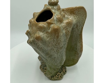 Jarrón de cerámica con forma de concha marina, esmalte verde y plateado con efecto goteo, estilo náutico costero vintage.