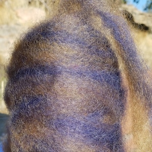 May include: A skein of yarn with a brown and purple color combination. The yarn is wound into a ball shape and is ready for knitting or crocheting.