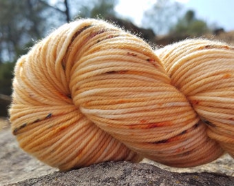 May include: A skein of yarn in a peach and cream color with flecks of orange and blue. The yarn is soft and fluffy and would be perfect for knitting or crocheting.