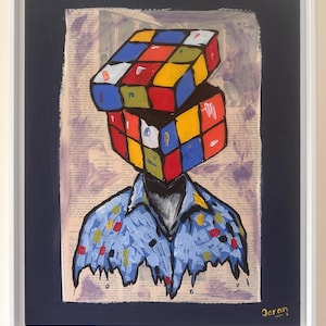 May include: Framed artwork featuring a person with a Rubik's Cube for a head. The cube is composed of red, blue, yellow, green, and white squares. The figure wears a blue shirt with colorful polka dots. The artwork is signed "Jaran".