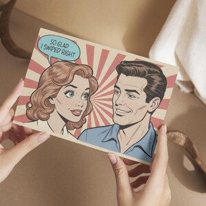 Puede incluir: Una tarjeta de felicitación de estilo vintage con una ilustración de cómic de una pareja sonriente. La mujer tiene el pelo castaño rojizo y el hombre tiene el pelo oscuro. Un bocadillo sobre la mujer dice: "SO GLAD I SWIPED RIGHT". El fondo tiene rayos rojos y beige.