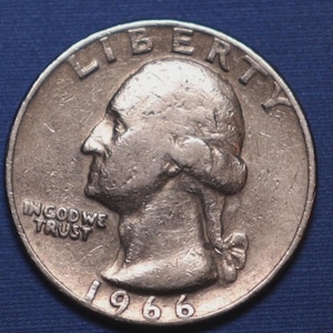 May include: A silver 1966 United States quarter coin. The coin features a profile of George Washington, the word "LIBERTY" at the top, and "IN GOD WE TRUST" and the date "1966" at the bottom.