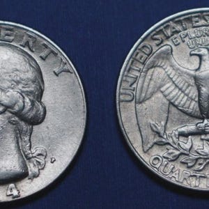 May include: Two silver quarter dollar coins. One coin features a profile of George Washington and the year 1984. The other coin shows an eagle with outstretched wings, the words "United States of America" and "Quarter Dollar."
