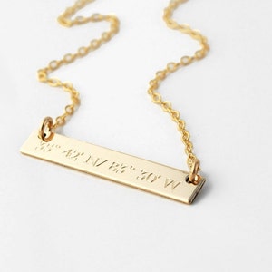 May include: Gold bar necklace with a delicate chain and a personalized inscription of coordinates: 42° N 83° 30' W.