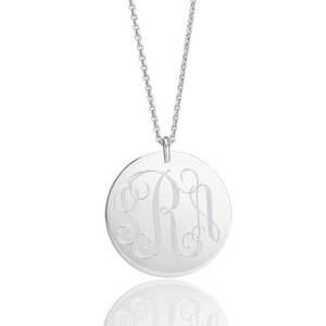 May include: A silver necklace with a round pendant featuring a monogrammed design. The pendant has a script font with the letters "S R H" engraved on it.
