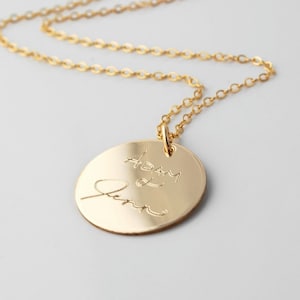 May include: Gold necklace with a round pendant featuring the handwritten names "Adam & Jenn" engraved on the front.