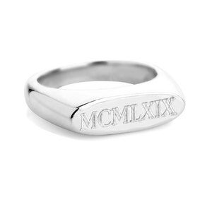 May include: A silver signet ring with a raised oval top engraved with the Roman numerals MCMXIX.