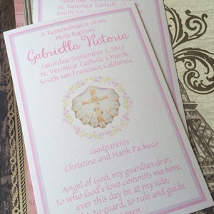 May include: Two baptism announcement cards with pink and white borders. The cards feature the name "Gabriella Victoria" in pink script, along with the date and location of the baptism. A seashell with a cross is in the center.