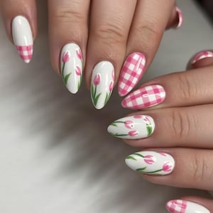 May include: Oval nail art with a white base, decorated with pink tulip designs and pink gingham patterns. The tulips have green stems and leaves. The gingham pattern is pink and white.