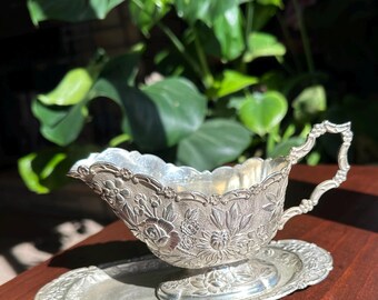 Salsera antigua bañada en plata con intrincado diseño floral cincelado y plato base a juego.