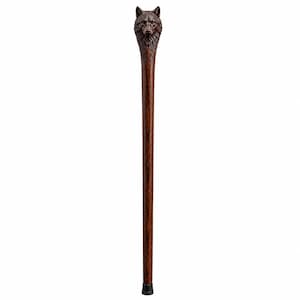 Puede incluir: Un bastón de madera de color marrón oscuro con un mango tallado a mano que representa una cabeza de lobo. El cuerpo del bastón es recto y cilíndrico con un acabado pulido y liso, finalizando en una contera de goma negra en la base.