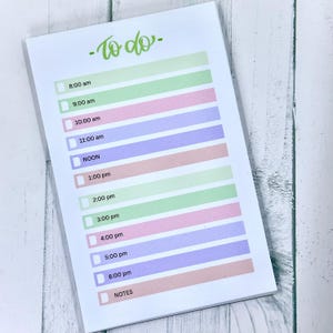 May include: A white notepad with a pastel color scheme, featuring a "To do" list. The list includes times from 8:00 am to 6:00 pm, with a section for notes. The text "To do" is in green script.