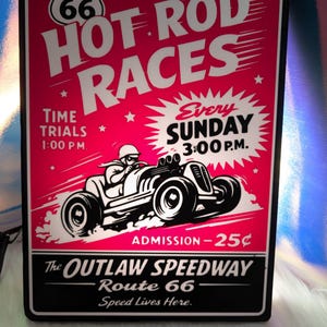 May include: A vintage-style sign with a red background and white text promoting "HOT ROD RACES." The sign features a black and white illustration of a race car and the text "The OUTLAW SPEEDWAY Route 66 Speed Lives Here."