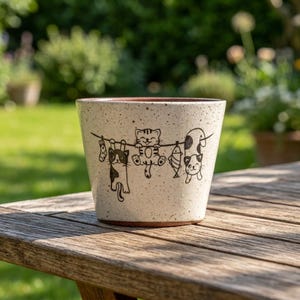Può includere: Una tazza di ceramica bianca con manico nero e la scritta "But First, Coffee" in grassetto nero. La tazza è posta su uno sfondo sfocato, che suggerisce un'atmosfera accogliente.