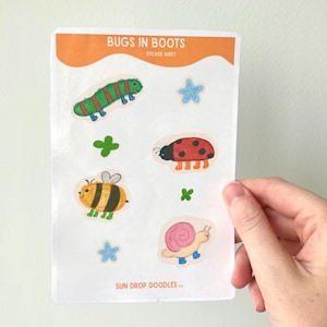 May include: A white sticker sheet titled BUGS IN BOOTS featuring colorful illustrations of a green caterpillar, a red ladybug, a yellow and black bee, and a pink snail, all wearing blue boots, plus two blue stars and two green clovers.