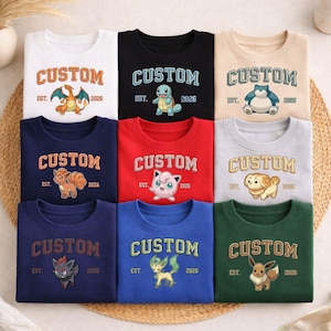 May include: Nine crewneck sweatshirts in various colors, each featuring a different cartoon character design. The word "CUSTOM" is arched across the top, with "EST. 2026" below. Colors include white, black, tan, navy, red, gray, blue, and green.