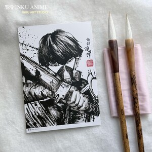 Puede incluir: Una impresión artística de anime en blanco y negro que presenta un personaje con un arma. Dos pinceles de caligrafía con mangos de madera y puntas blancas descansan sobre una tela rosa. La impresión tiene texto japonés y las palabras "INKU ANIME" y "INKU ART STUDIO".