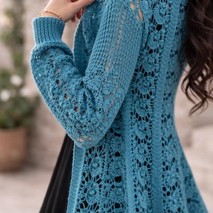以下が含まれることがあります： 鮮やかな青緑色の、オープンフロントの長袖かぎ針編みカーディガン。複雑な花柄と透かし模様が衣服全体に見られます。袖と背中には詳細な模様があります。このカーディガンは、どんなワードローブにもスタイリッシュに加えることができます。