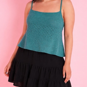 May include: Teal crochet top with thin straps and a flared hem, paired with a black tiered skirt. The top has a textured pattern and a square neckline. The skirt is made of a flowing fabric.