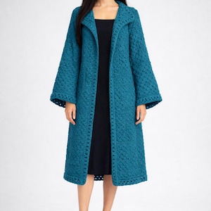 May include: A long, teal-coloured, open-front coat with a textured, woven design. The coat has long sleeves and a collar. The person in the image is wearing a black dress and black sandals. The coat is knee-length.
