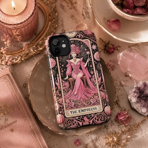 Op de afbeelding: Zwarte en roze telefoonhoes met een tarotkaartontwerp. De illustratie toont een vrouw in een roze jurk, met de woorden "THE EMPRESS" onderaan. De hoes is versierd met kaarsen en bloemmotieven.