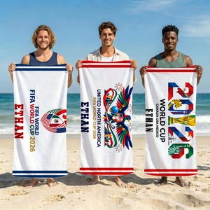 May include: Three white rectangular beach towels featuring FIFA World Cup 2026 branding. Each towel displays the name ETHAN in bold letters, along with colorful graphic designs including a soccer ball, an eagle, and the year 2026 in large font.
