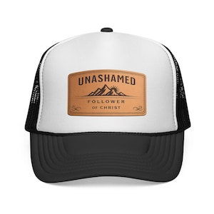 Peut inclure: Casquette de camionneur noire et blanche avec un panneau avant blanc. Le panneau avant présente un écusson rectangulaire marron avec les mots "UNASHAMED" au-dessus d'un graphique de montagne et "FOLLOWER OF CHRIST" en dessous.