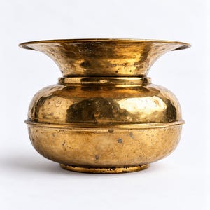 May include: A round, hammered brass bowl with a wide, flared rim and a distinct horizontal ridge encircling the center of the body. The metal surface displays a weathered, aged patina with visible dark spots and a warm, metallic gold tone.